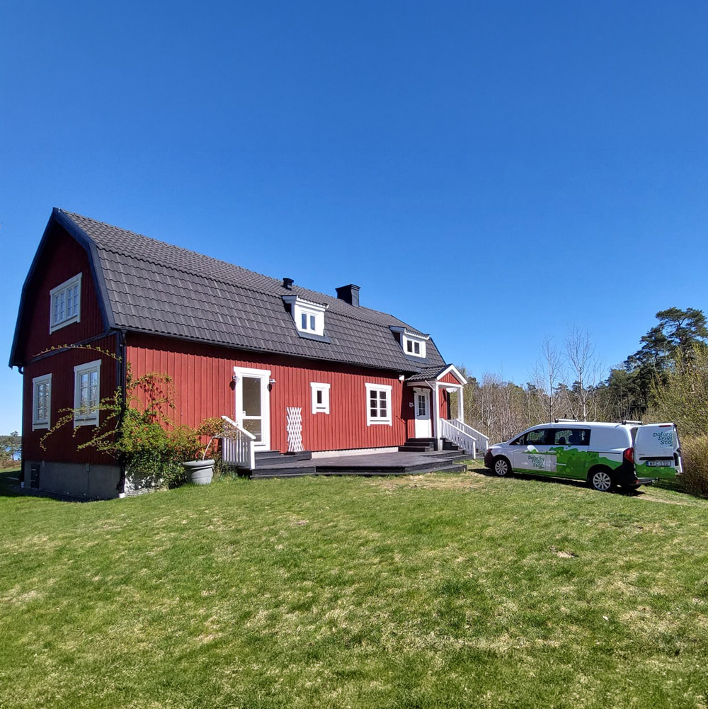 En skåpbil med företagets logga parkerad framför en röd villa